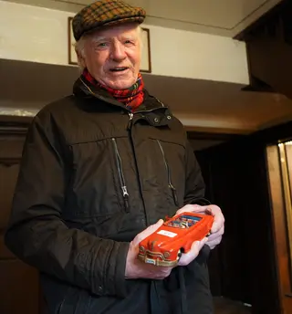 Ein älterer Herr mit einem roten Modellauto.