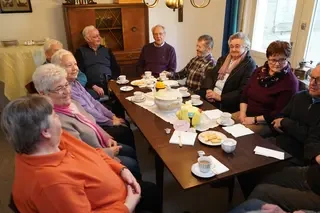 Mitglieder und Kunden des Repaircafés sitzen bei Kaffee und Kuchen zusammen.