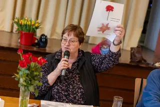 Frau hält Mikro in der Hand und hält Plakat hoch