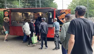 Personen stehen an einem Grillwagen an.