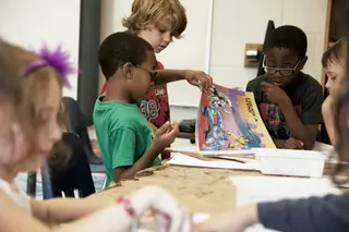 Das Bild zeigt eine Gruppe Jungen, die zusammen einen Comic durchblättern.