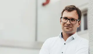 Ein Mann in einem weißen Hemd mit einer schwarzen Brille.