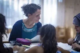 Eine Frau hilft Kindern bei ihren Hausaufgaben.