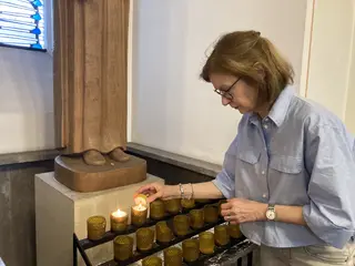 Christiane Krebs zündet eine Kerze an einer Heiligenstatue an.