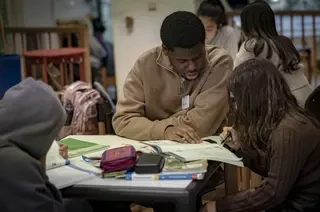 Das Bild zeigt eine Gruppe Menschen, die gemeinsam Hausaufgaben machen.