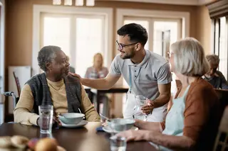 Ein Junger Mann bewirtet einen älteren Herrn und eine ältere Dame.