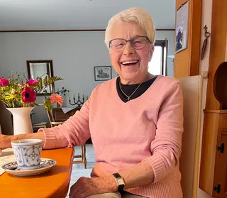 Ältere Dame sitzt am Kaffeetisch